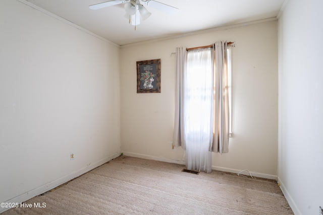 spare room with ceiling fan, crown molding, and light carpet