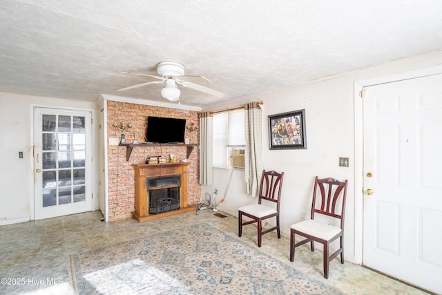 living room with ceiling fan, a fireplace, and a textured ceiling