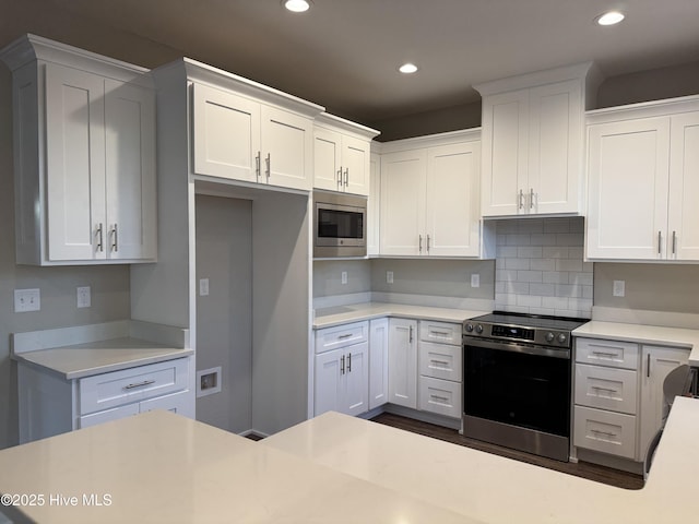 kitchen featuring stainless steel microwave, white cabinetry, and range