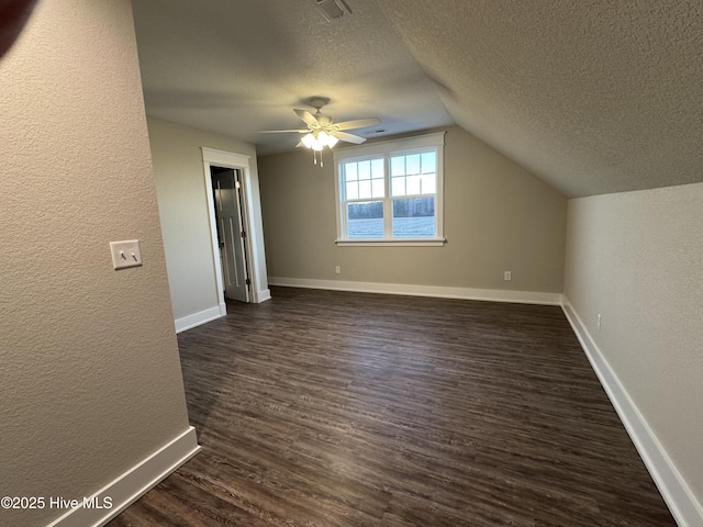 additional living space with a textured ceiling, dark wood-type flooring, lofted ceiling, and ceiling fan