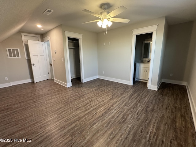 unfurnished bedroom with ceiling fan, connected bathroom, dark wood-type flooring, a closet, and a textured ceiling