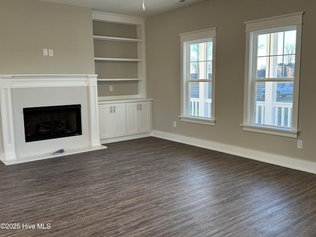 unfurnished living room with dark hardwood / wood-style flooring and built in features