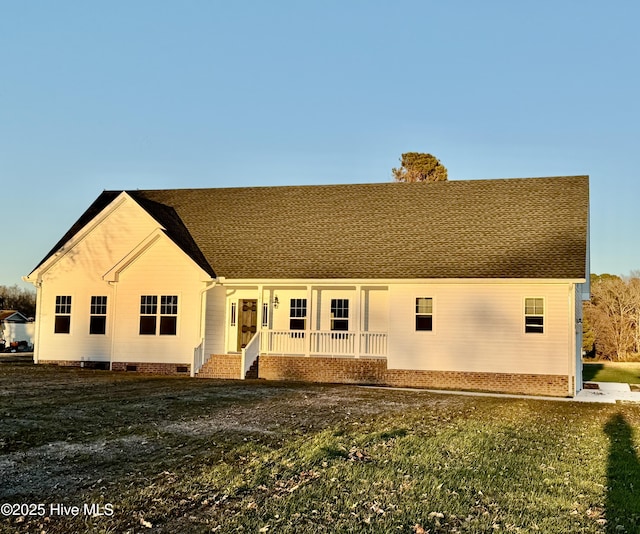 rear view of house with covered porch and a lawn