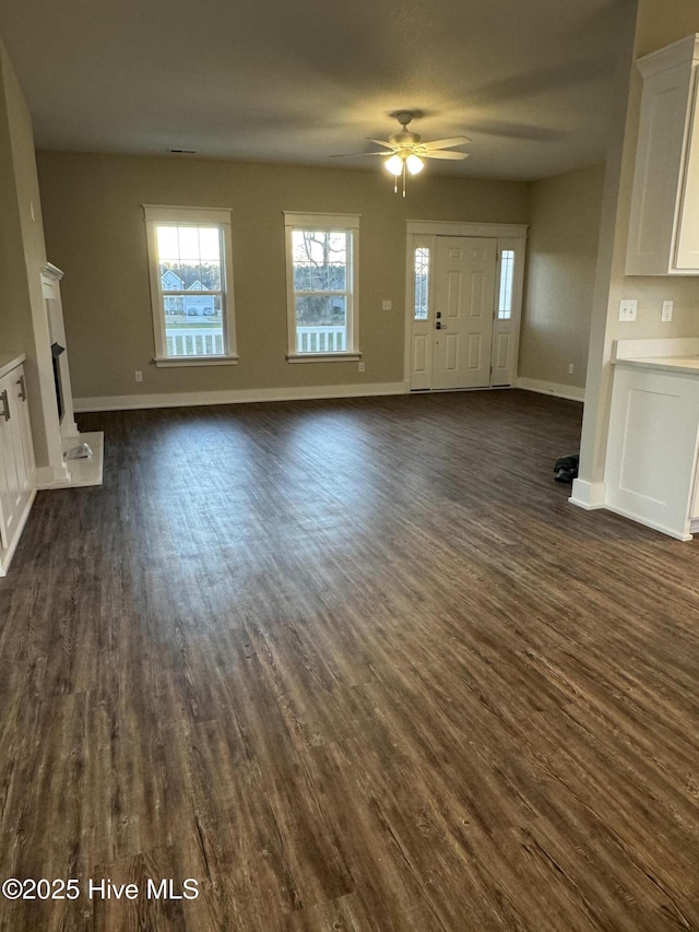 unfurnished living room featuring ceiling fan and dark hardwood / wood-style floors