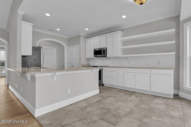 kitchen featuring backsplash, stainless steel appliances, sink, white cabinets, and a breakfast bar area