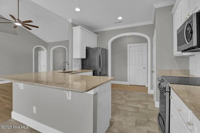 kitchen with a kitchen bar, appliances with stainless steel finishes, ceiling fan, sink, and white cabinets