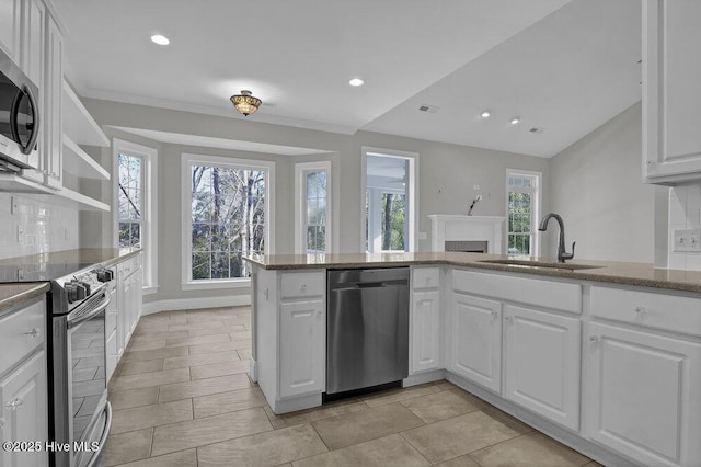 kitchen with decorative backsplash, kitchen peninsula, stainless steel appliances, sink, and white cabinets