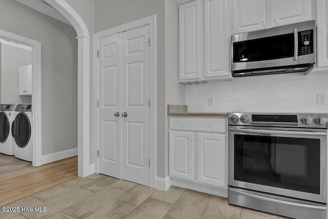 kitchen with white cabinets, appliances with stainless steel finishes, light hardwood / wood-style floors, and washing machine and clothes dryer