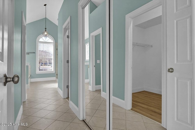 hall featuring a notable chandelier, lofted ceiling, and light tile patterned floors