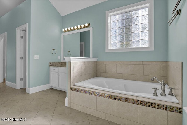 bathroom featuring tile patterned floors, vanity, lofted ceiling, and tiled tub