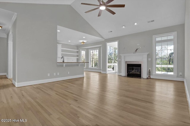 unfurnished living room with a wealth of natural light, light hardwood / wood-style flooring, ceiling fan, and high vaulted ceiling