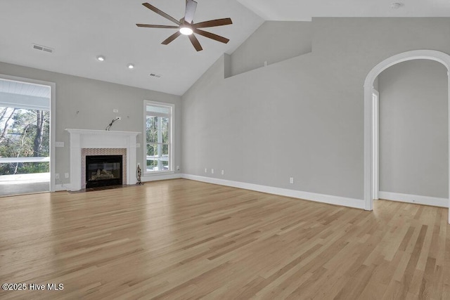 unfurnished living room featuring ceiling fan, light hardwood / wood-style flooring, high vaulted ceiling, and a healthy amount of sunlight