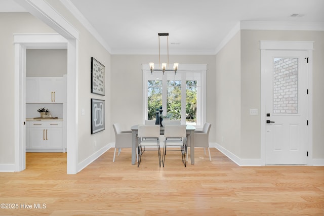 dining area with light hardwood / wood-style flooring, ornamental molding, and a chandelier