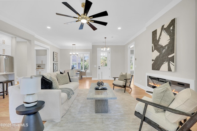 living room with crown molding, light hardwood / wood-style flooring, and ceiling fan with notable chandelier