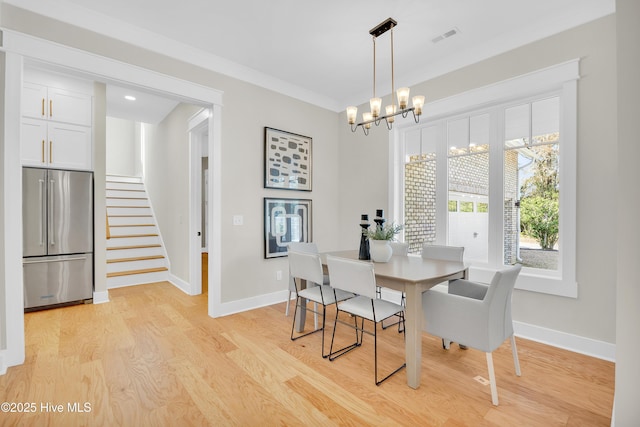 dining room featuring crown molding, light hardwood / wood-style flooring, and a notable chandelier