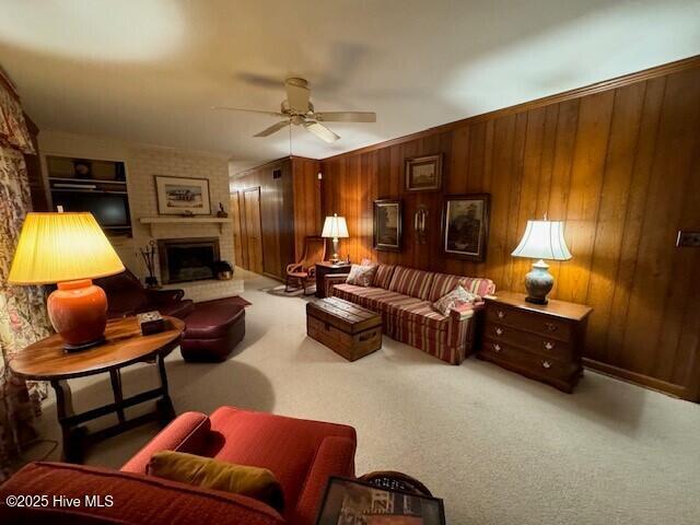 carpeted living room featuring ceiling fan, a fireplace, and wooden walls