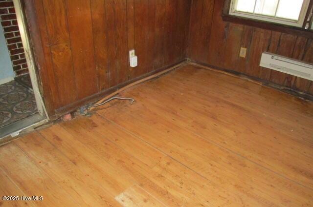 53 Bowmanville Dr, Fairmont, NC 28340 - spare room featuring wood-type flooring, a baseboard heating unit, and wood walls