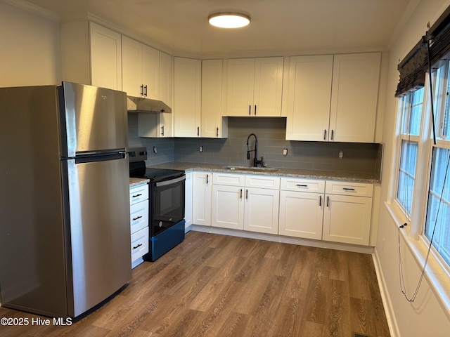 kitchen with black electric range oven, white cabinets, sink, stainless steel fridge, and light stone counters