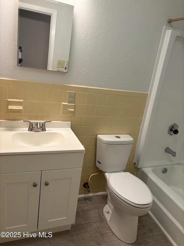 full bathroom featuring vanity, bathtub / shower combination, tile walls, and toilet