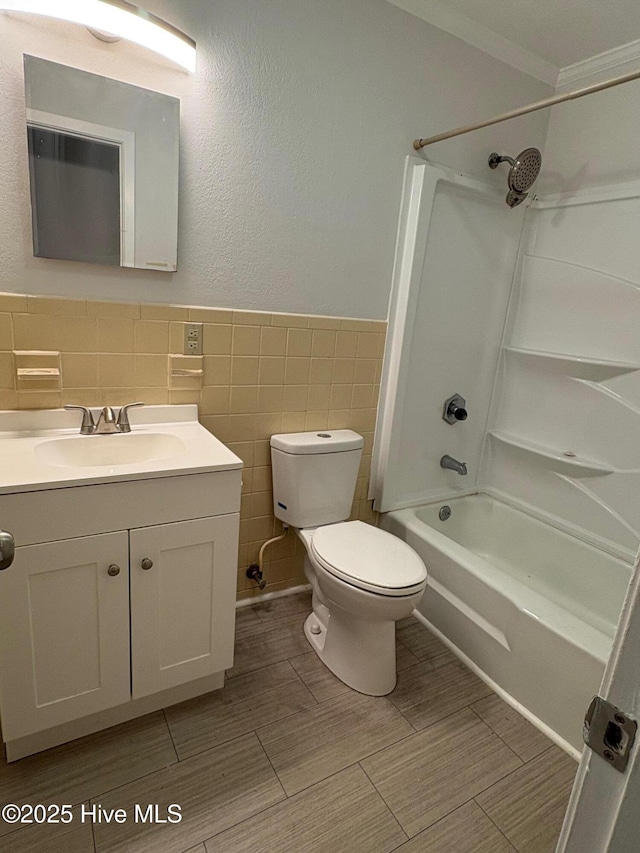 full bathroom with tub / shower combination, vanity, crown molding, tile walls, and toilet