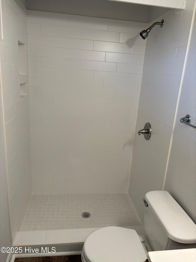 bathroom featuring toilet and a tile shower