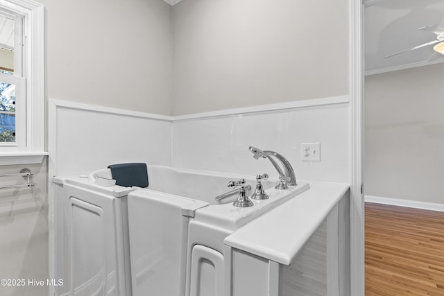 bathroom with ceiling fan, a bathtub, hardwood / wood-style floors, and ornamental molding