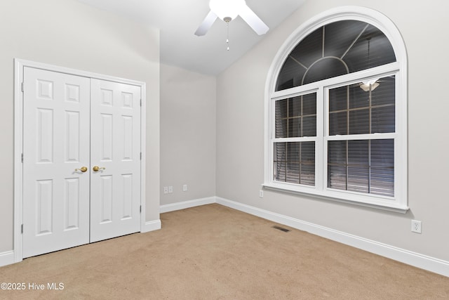 unfurnished bedroom with ceiling fan, light colored carpet, lofted ceiling, and a closet