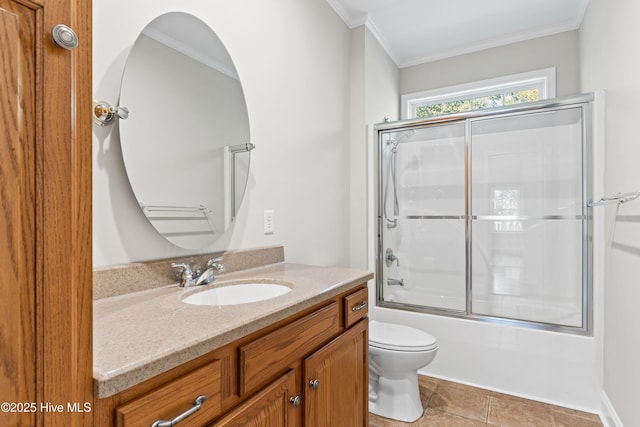 full bathroom with tile patterned flooring, crown molding, bath / shower combo with glass door, toilet, and vanity