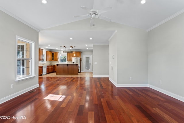 unfurnished living room featuring ceiling fan, dark hardwood / wood-style flooring, ornamental molding, and vaulted ceiling