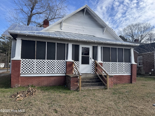 rear view of property with a lawn and a sunroom