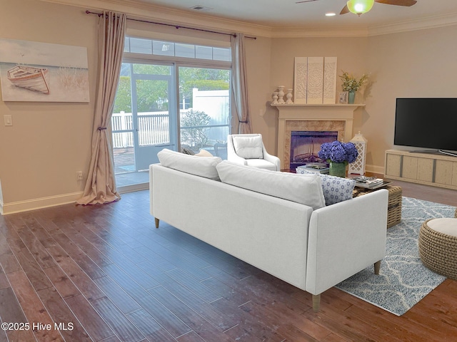 living room with dark wood-type flooring, ornamental molding, and ceiling fan