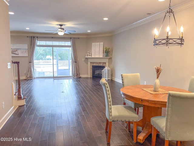 dining space with crown molding, ceiling fan with notable chandelier, and dark hardwood / wood-style flooring