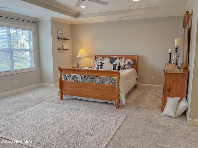 bedroom with ceiling fan, ornamental molding, a tray ceiling, and light colored carpet