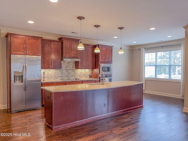 kitchen with hanging light fixtures, a center island with sink, ornamental molding, and appliances with stainless steel finishes