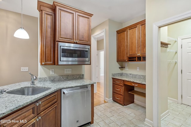 kitchen featuring light stone counters, sink, decorative light fixtures, and appliances with stainless steel finishes