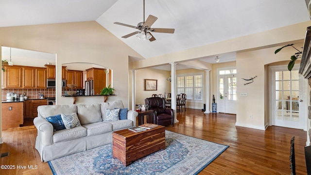 living room featuring ceiling fan, dark wood-type flooring, high vaulted ceiling, and decorative columns