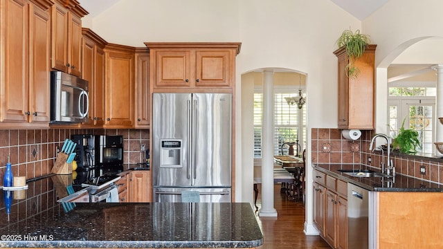 kitchen with stainless steel appliances, lofted ceiling, decorative columns, backsplash, and sink