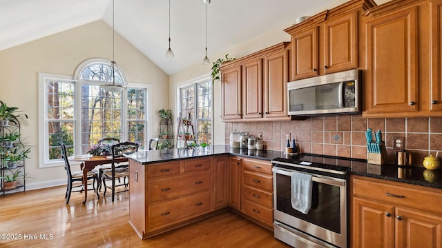 kitchen with decorative light fixtures, decorative backsplash, light wood-type flooring, appliances with stainless steel finishes, and dark stone countertops