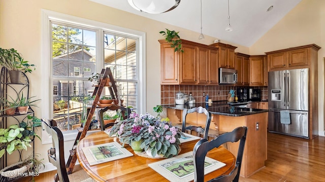 kitchen with stainless steel appliances, lofted ceiling, tasteful backsplash, kitchen peninsula, and light hardwood / wood-style flooring