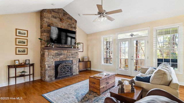 living room featuring vaulted ceiling, french doors, a wealth of natural light, and a stone fireplace