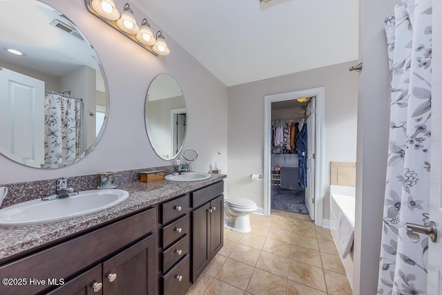 bathroom with tile patterned floors, vanity, a relaxing tiled tub, and toilet