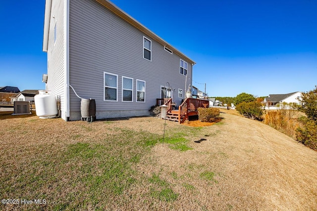 back of house with a lawn, a deck, and central AC