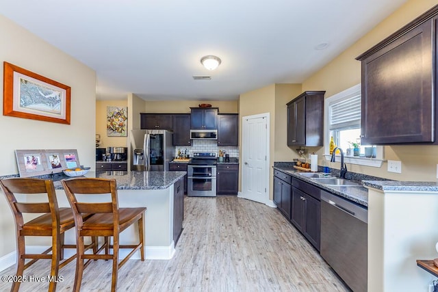 kitchen featuring dark brown cabinetry, sink, a center island, a breakfast bar area, and appliances with stainless steel finishes