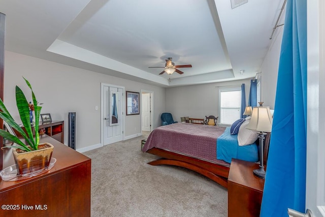 carpeted bedroom featuring ceiling fan and a raised ceiling