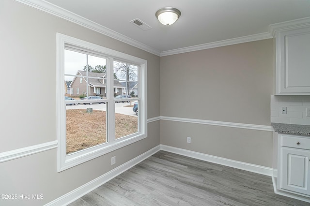 unfurnished dining area with crown molding and light wood-type flooring