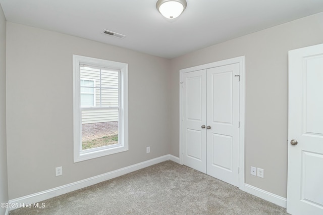 unfurnished bedroom with a closet and light colored carpet