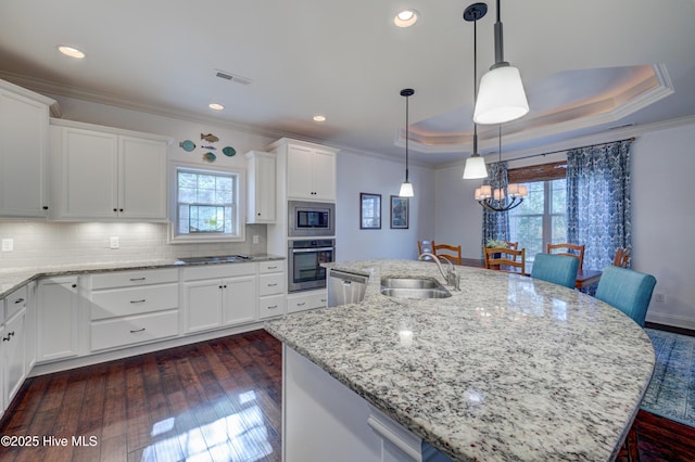 kitchen featuring sink, appliances with stainless steel finishes, a raised ceiling, an island with sink, and white cabinets