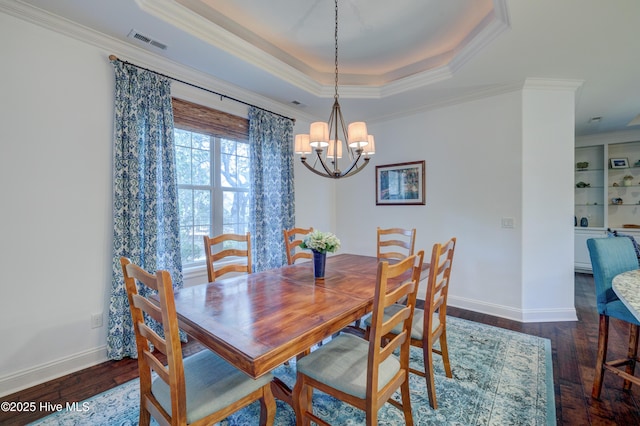 dining area with a raised ceiling, ornamental molding, a notable chandelier, and dark hardwood / wood-style flooring