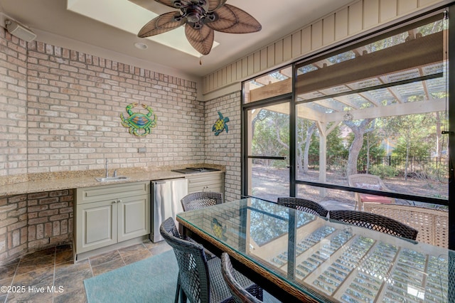 dining room featuring brick wall, sink, a wealth of natural light, and ceiling fan