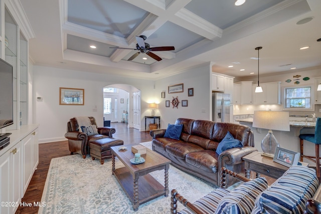 living room featuring dark wood-type flooring, ceiling fan, beam ceiling, coffered ceiling, and ornamental molding